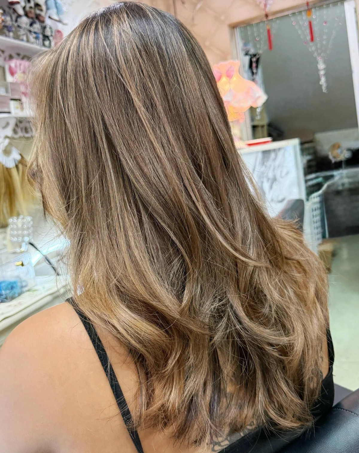 Oilly Hair Salon Bangkok で black hair color removal 施術後 — 立体感のあるやわらかな honey brown ash balayage のバックスタイル、健康的に見える仕上がり