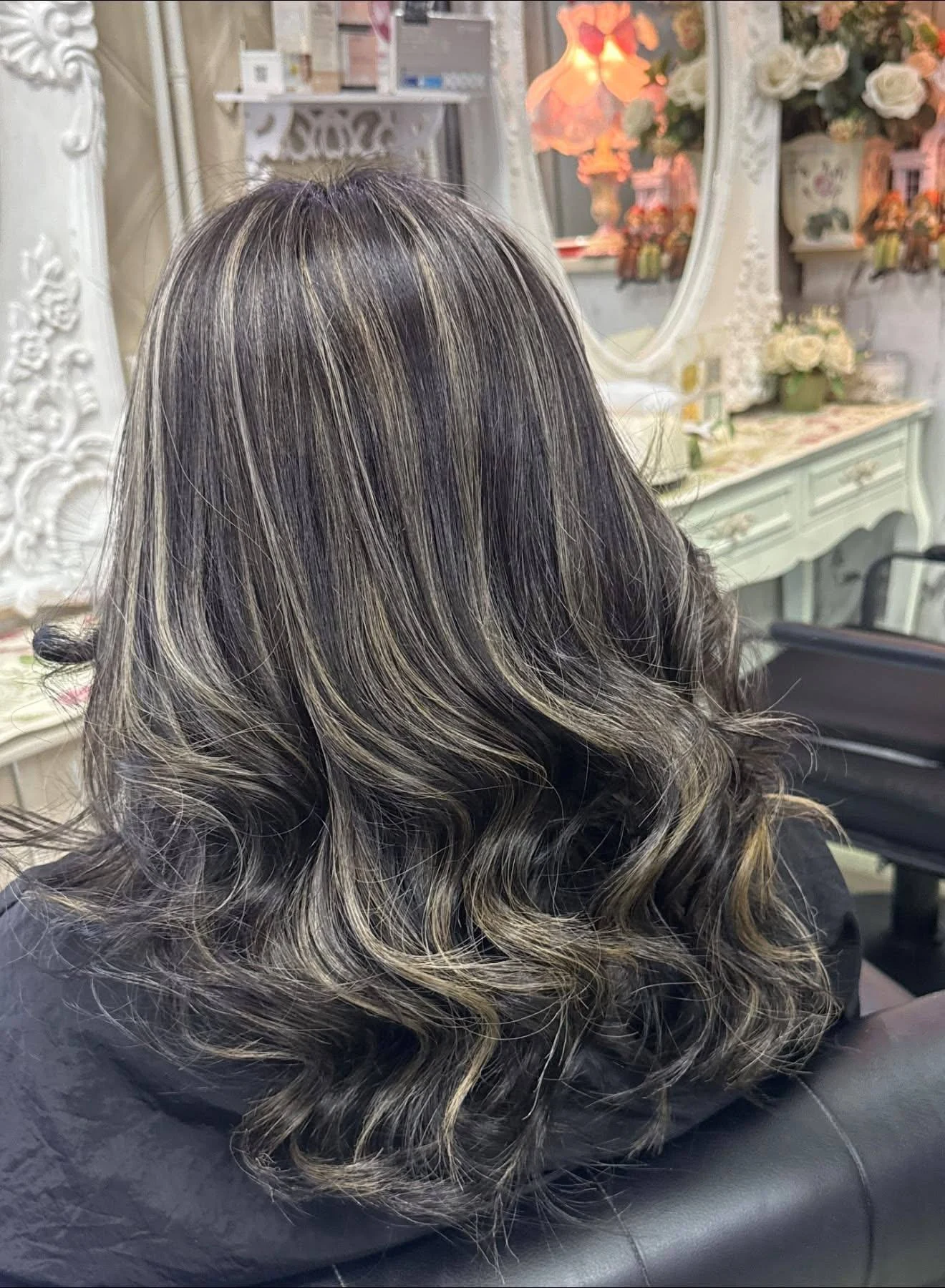 Back view of dark ash hair with dimensional ash-beige highlight ribbons and styled waves