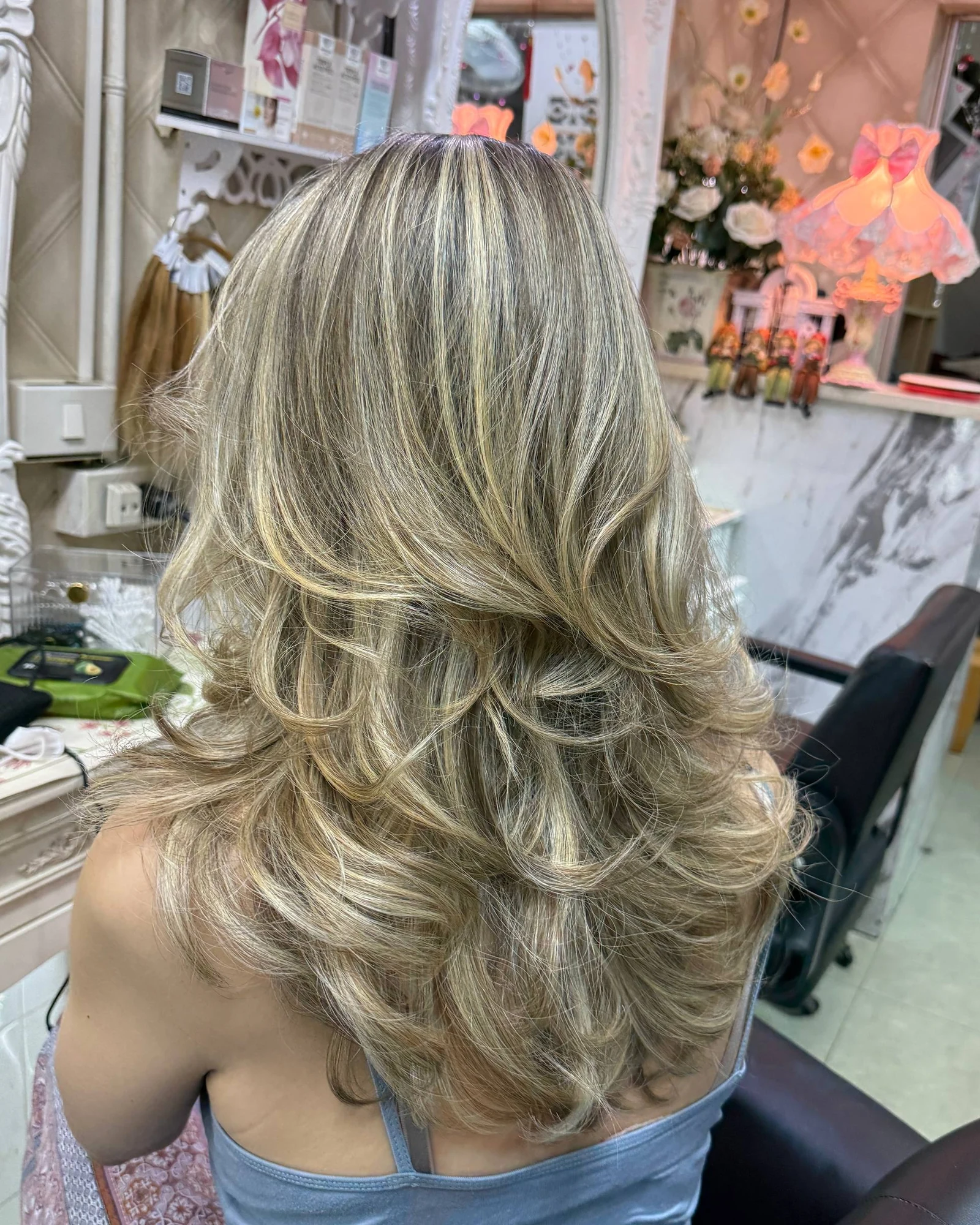 Back view of fine full-head blonde Baby Highlights dispersed across a natural blonde base at Oilly Hair Salon Bangkok