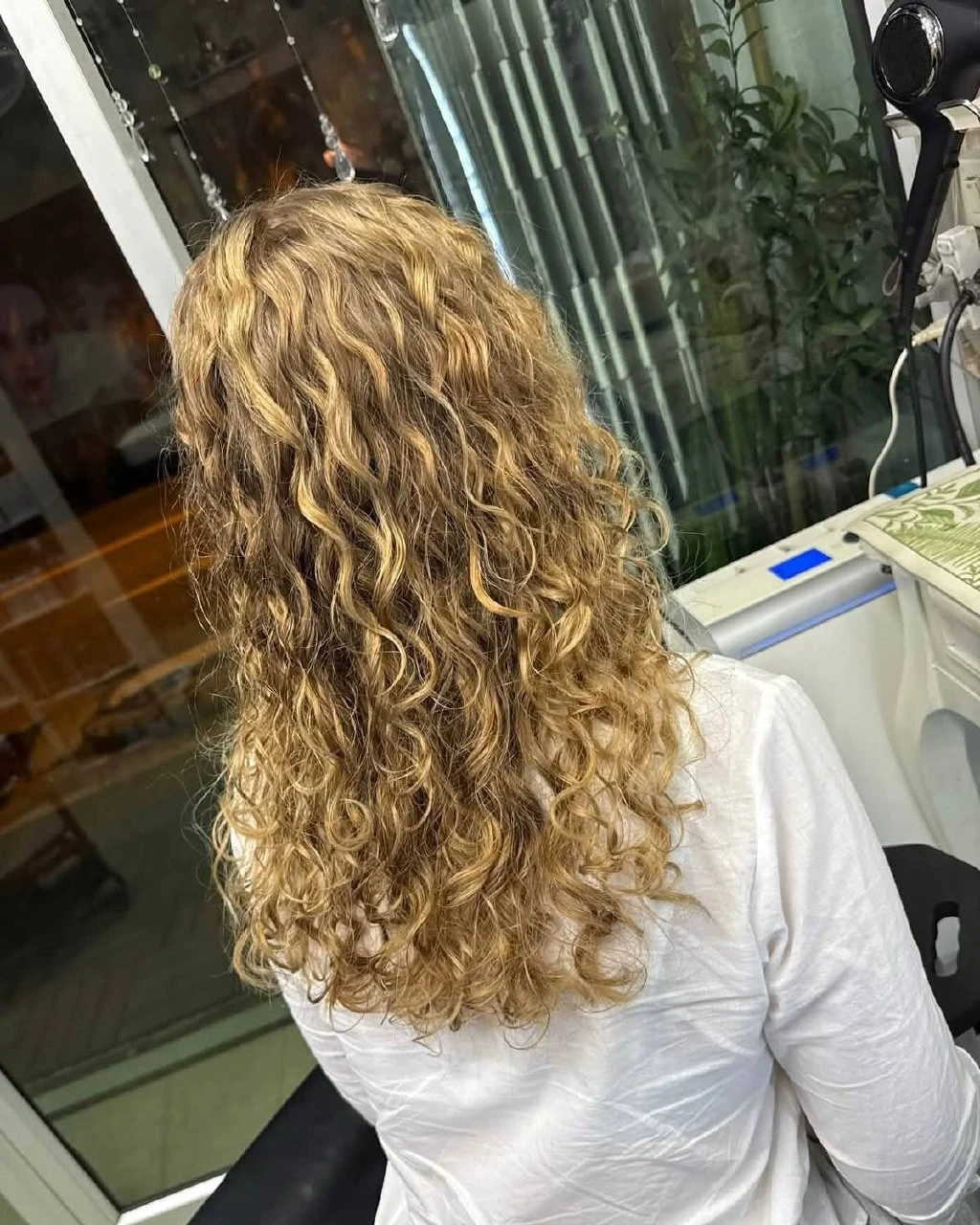 Cold perm with clearly defined natural S-waves on long blonde hair in Bangkok, back view
