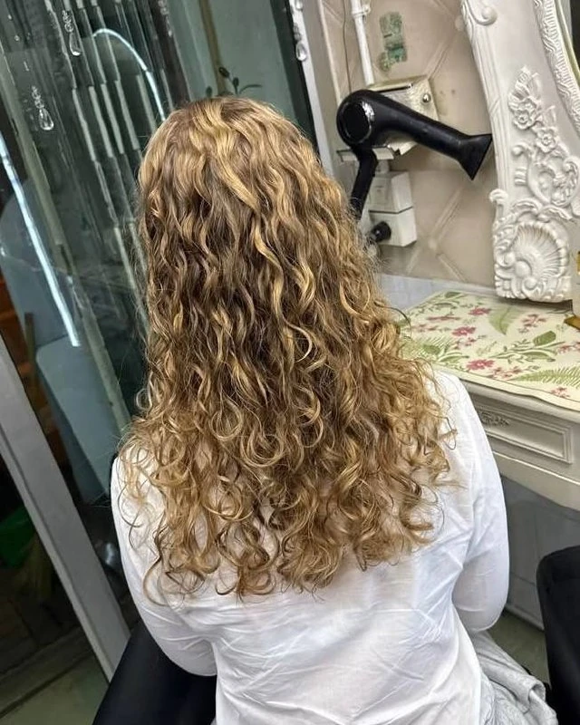 Soft, defined cold-perm S-waves on long blonde hair at Oilly Hair Salon Bangkok, second angle
